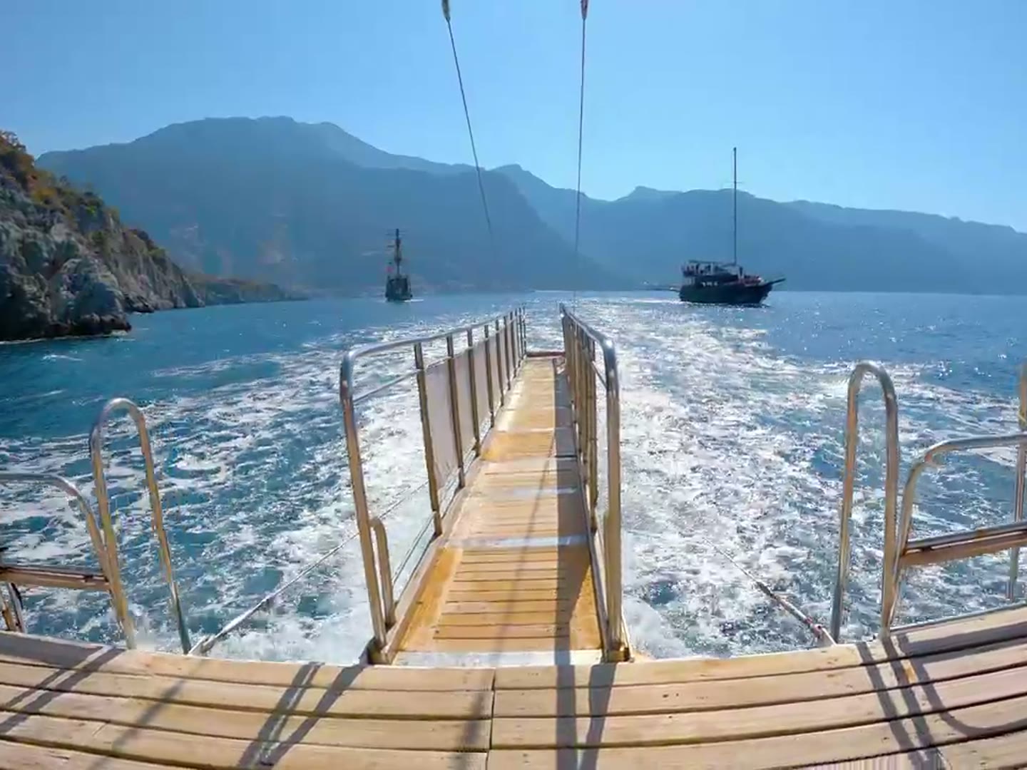 A crew member crossing the passerelle onto a yacht's swim platform